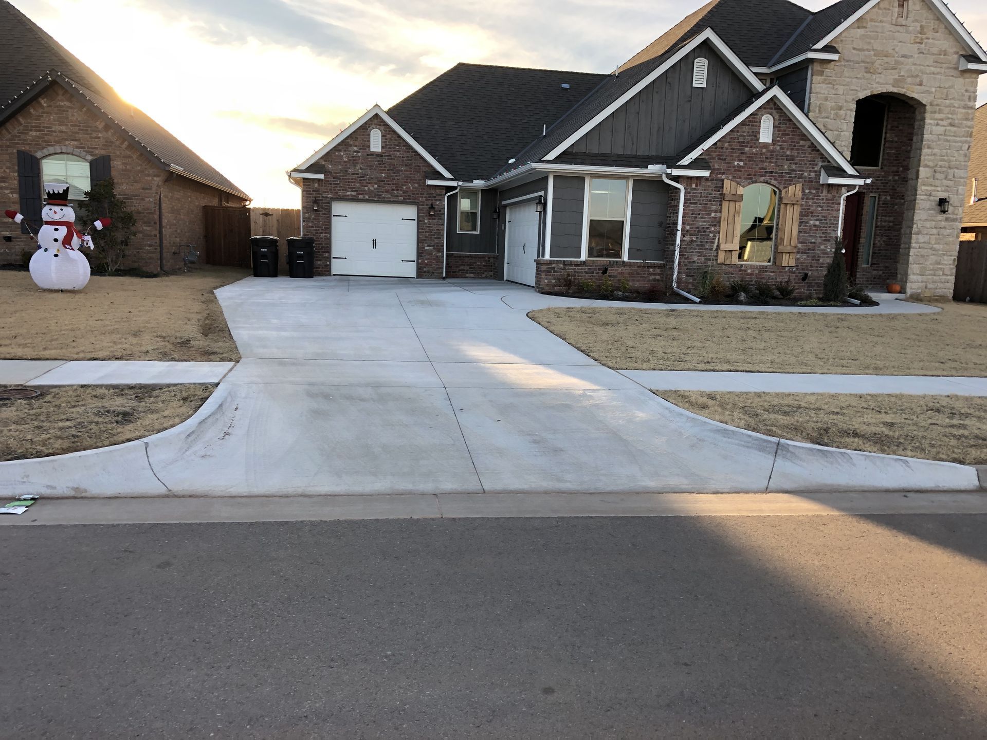 A house with a driveway. A snowman and sun are visible.