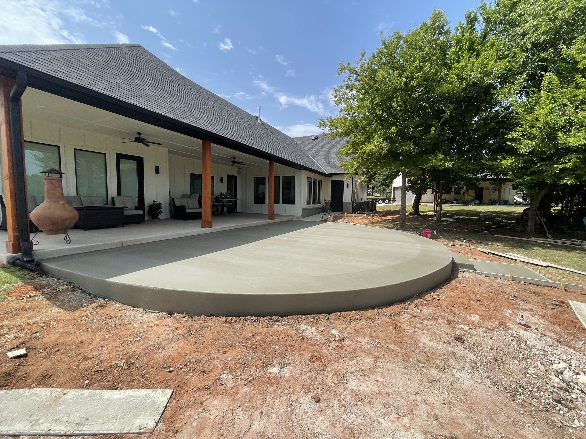 New concrete patio under construction next to a white house with a covered porch.