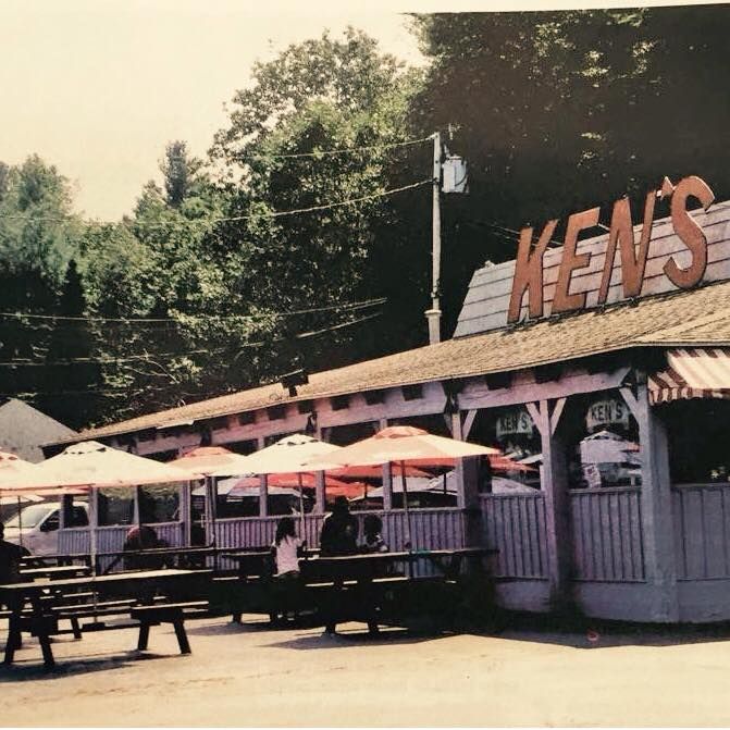 Outdoor diner with pink umbrellas and a large “MEANS” sign above the patio.