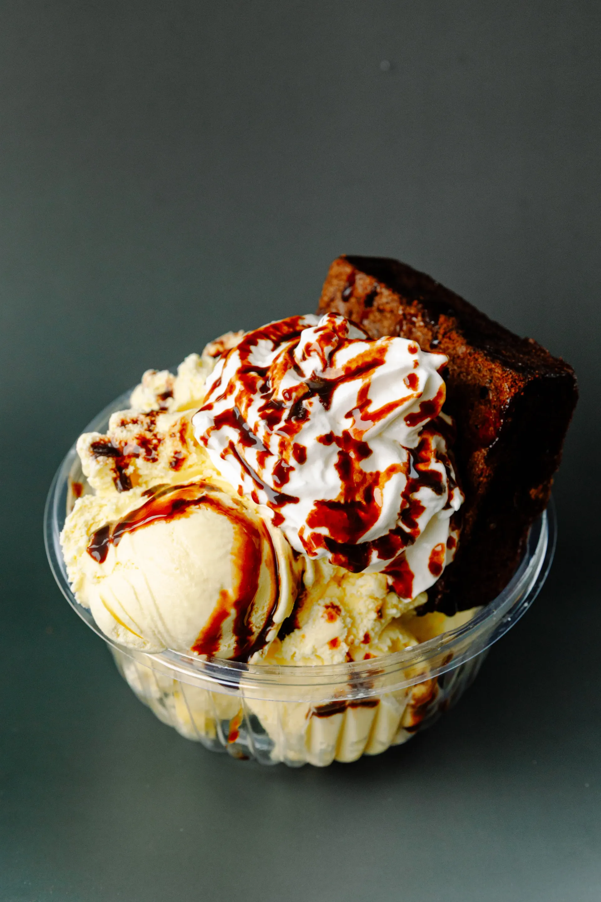 Ice cream sundae in a glass bowl with chocolate drizzle, brownie pieces, and whipped cream