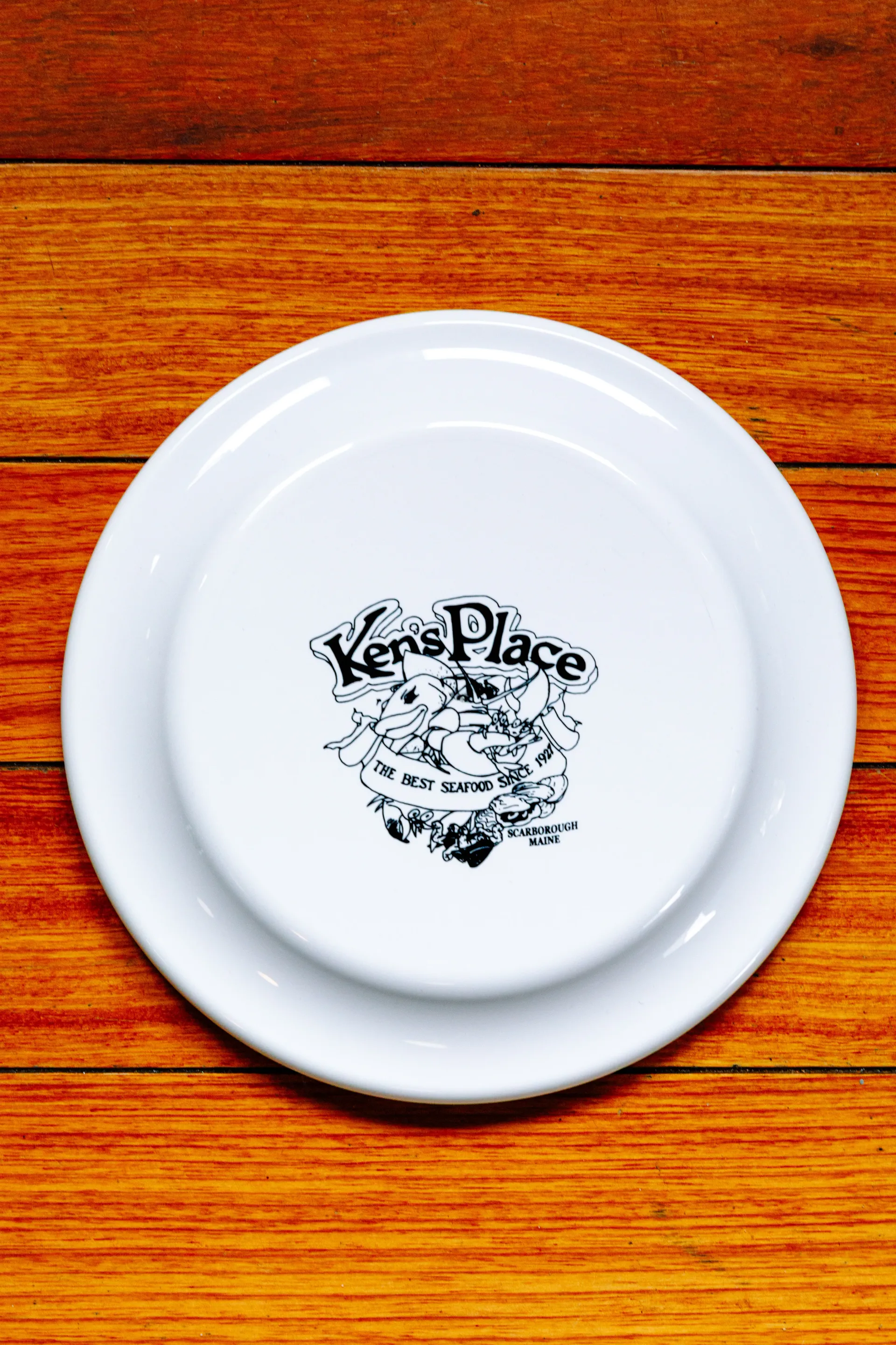 White plate with a black logo on a wooden table