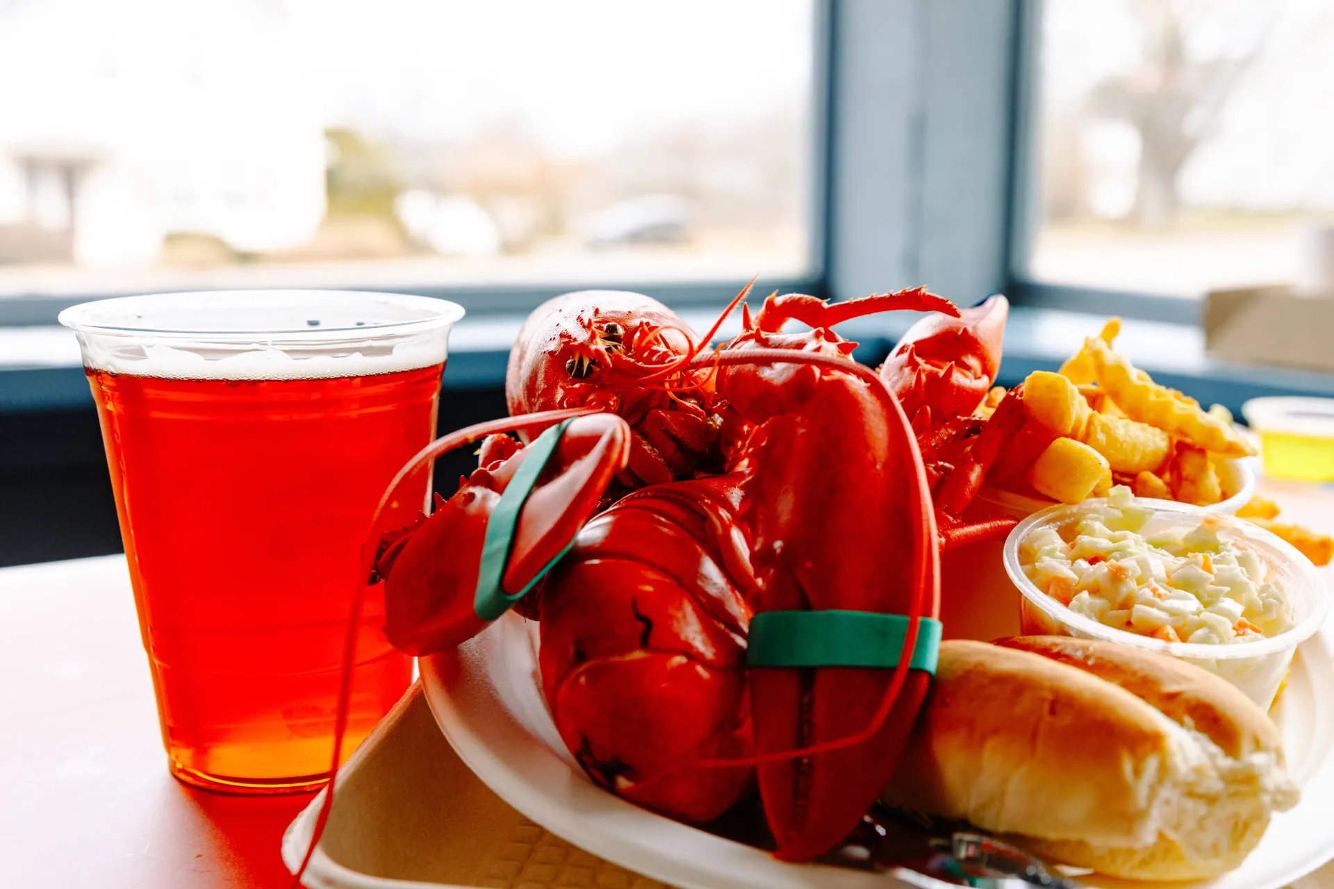 Red cocktail and lobster rolls with lemon wedges on a bright restaurant table
