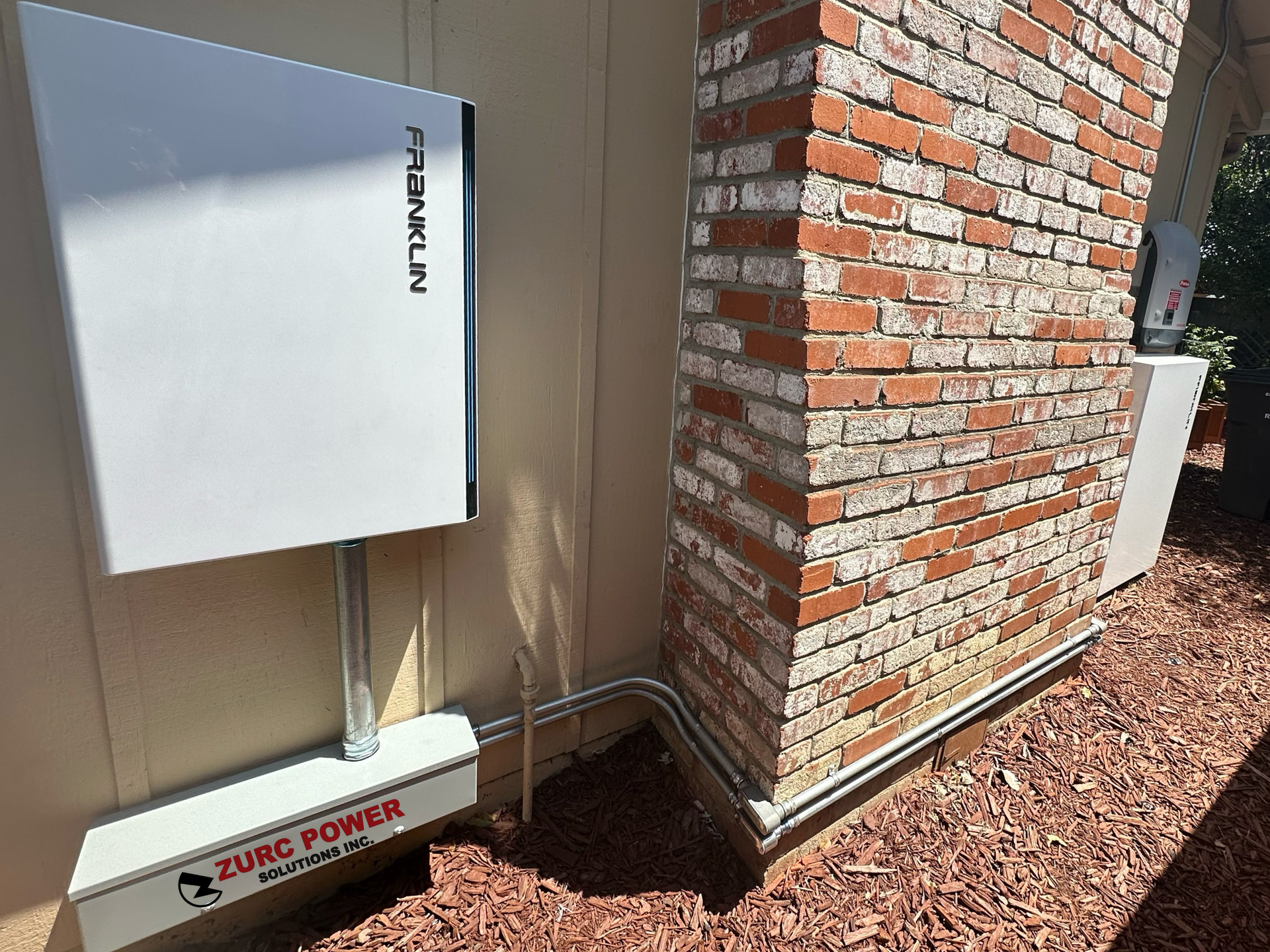 A white box is sitting on the side of a brick building.