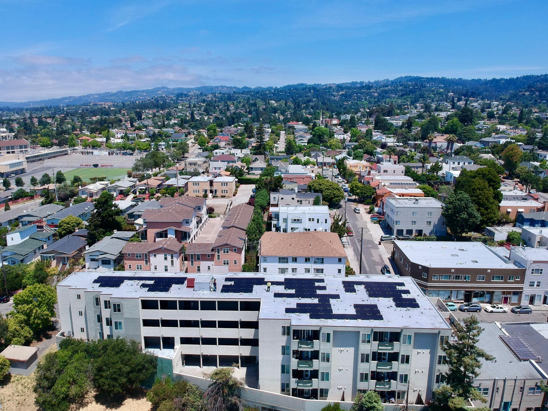 An aerial view of a city with a building with solar panels on the roof.