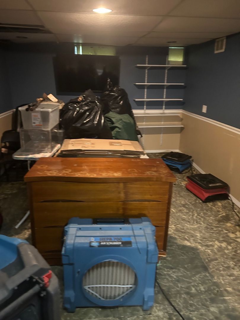 Commercial air movers and dehumidifier drying a water-damaged basement closet area