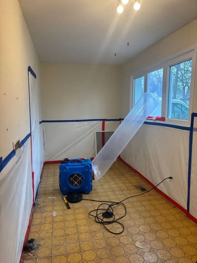 Technician in protective gear during asbestos removal in laundry room