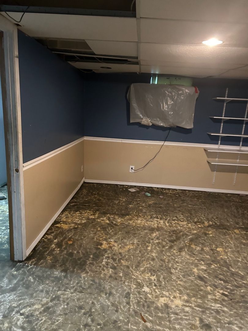 Basement living room cleared after pack-out with walls stripped and floor exposed