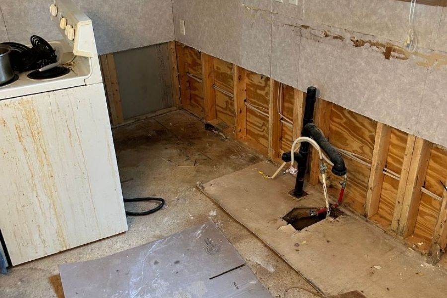 Kitchen water damage from a sink leak showing damaged cabinets and flooring