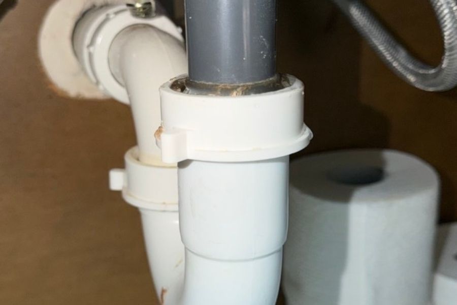 Leaking bathroom sink causing water damage to the cabinet and floor below