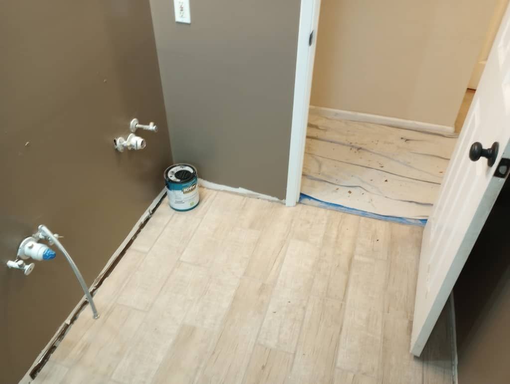 Fresh wood-look flooring installed in the restored bathroom