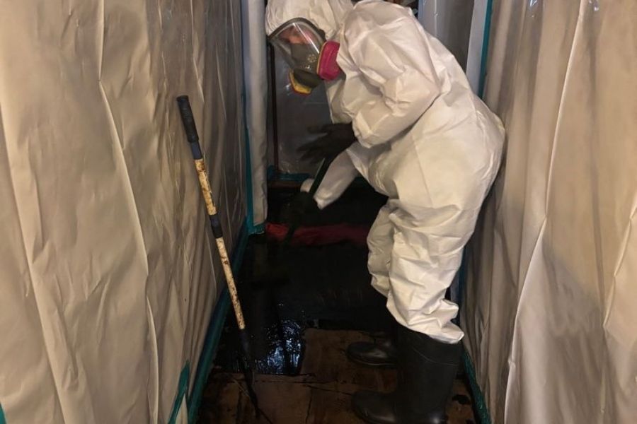 Certified technician in protective gear performing professional asbestos removal