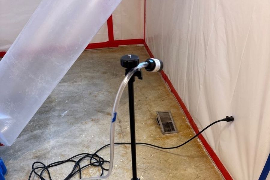 Certified technician in protective equipment performing professional asbestos removal in a home