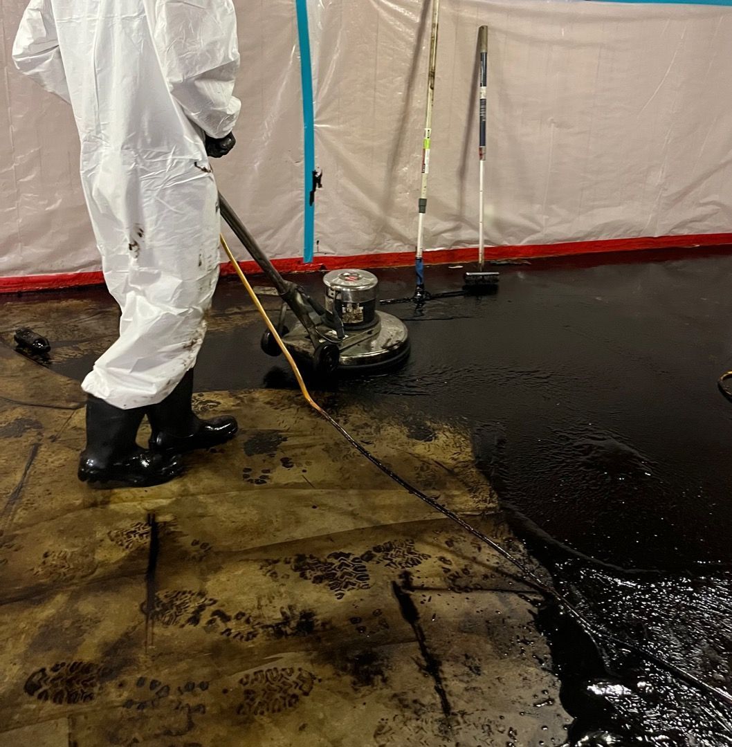 Professional asbestos removal underway in a water-damaged residential basement
