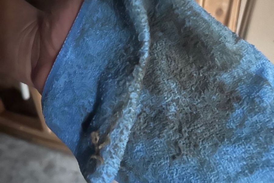 Visible black soot residue on a white cloth after wiping a fire-damaged surface
