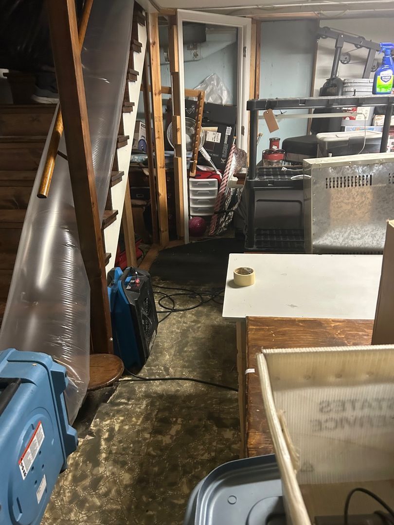 Basement living area during water damage restoration with air scrubber and drying equipment running