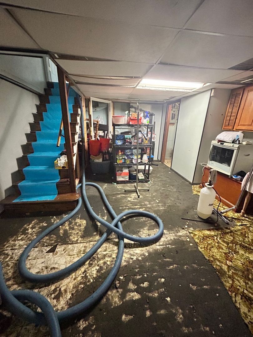 Truck-mounted water extraction hoses removing standing water from a flooded Florissant basement