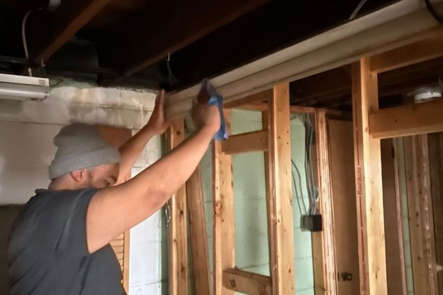 Restoration technician wiping soot from a wall surface after drywall demolition following a house fire
