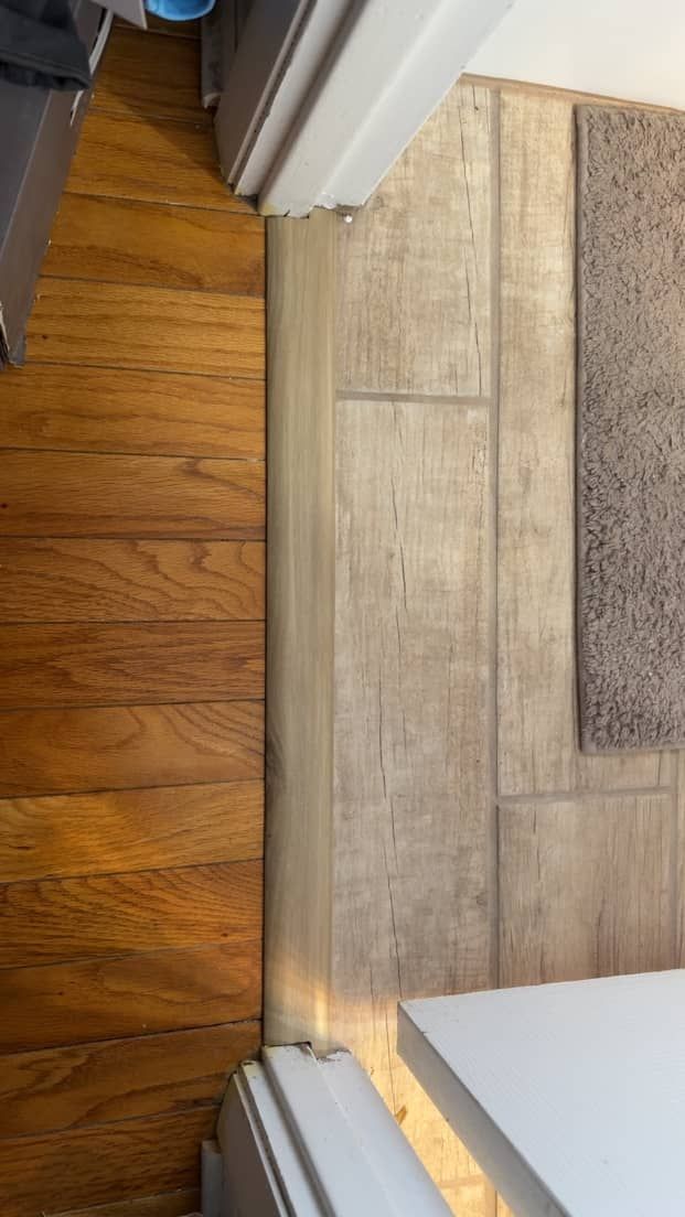 New wooden flooring meeting new bathroom flooring after water damage repair