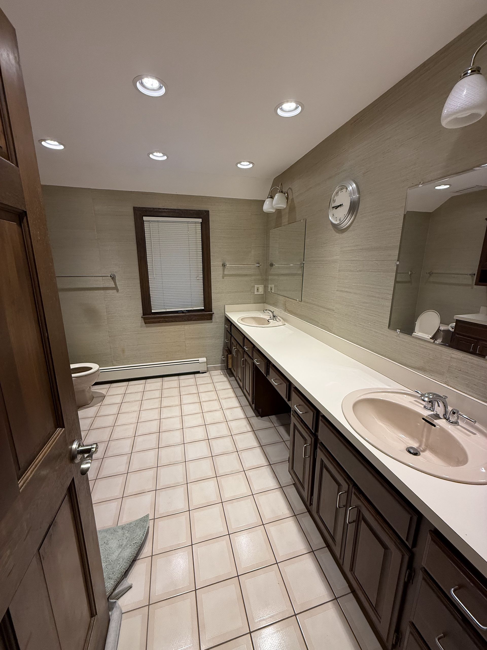 Bathroom with brown cabinets, sinks, and beige walls and flooring.
