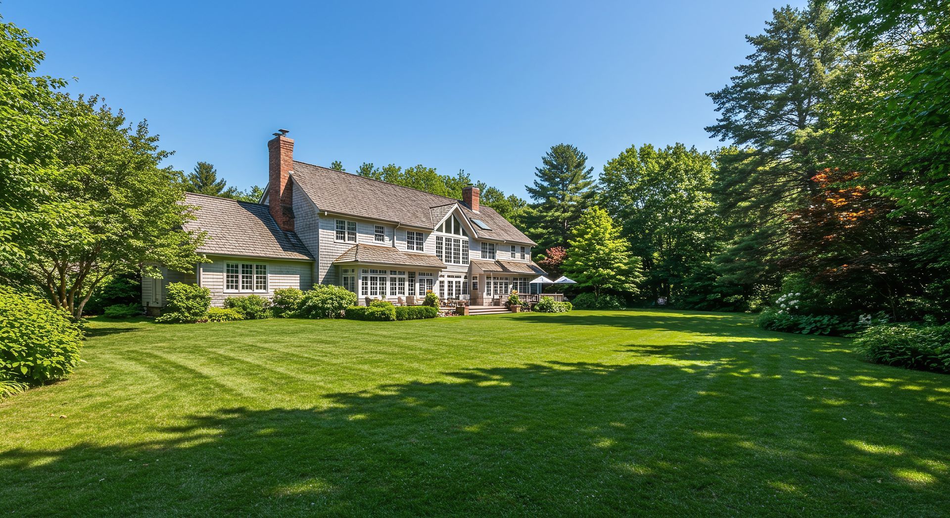 Large house with green lawn, trees, and blue sky.