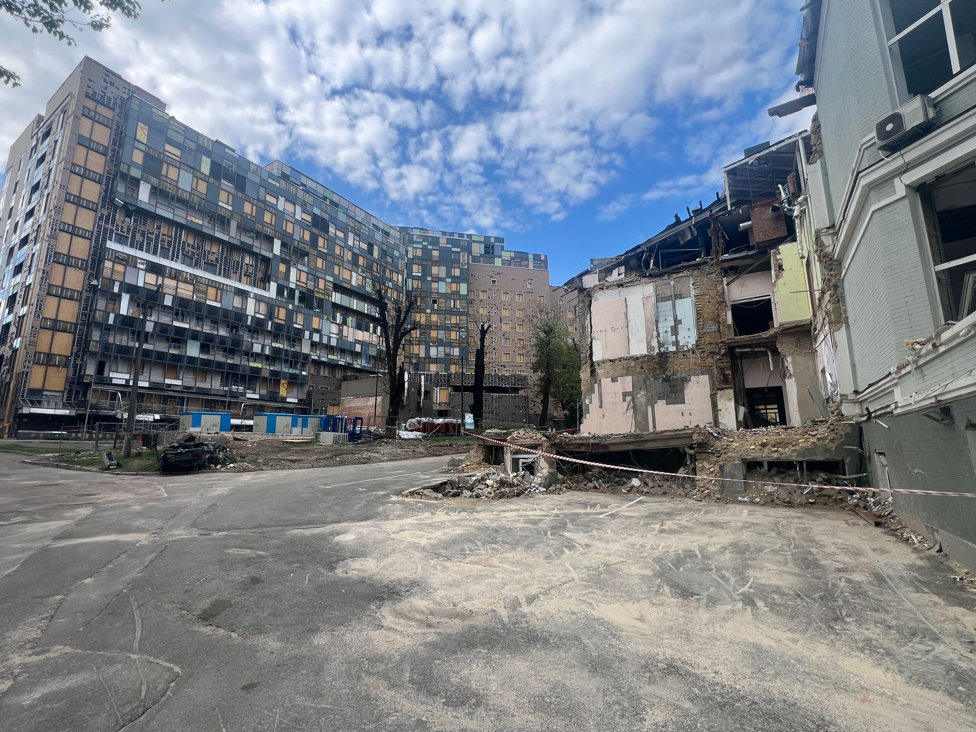 Skadede bygninger i bymiljø under en overskyet himmel, ruiner i forgrunnen.