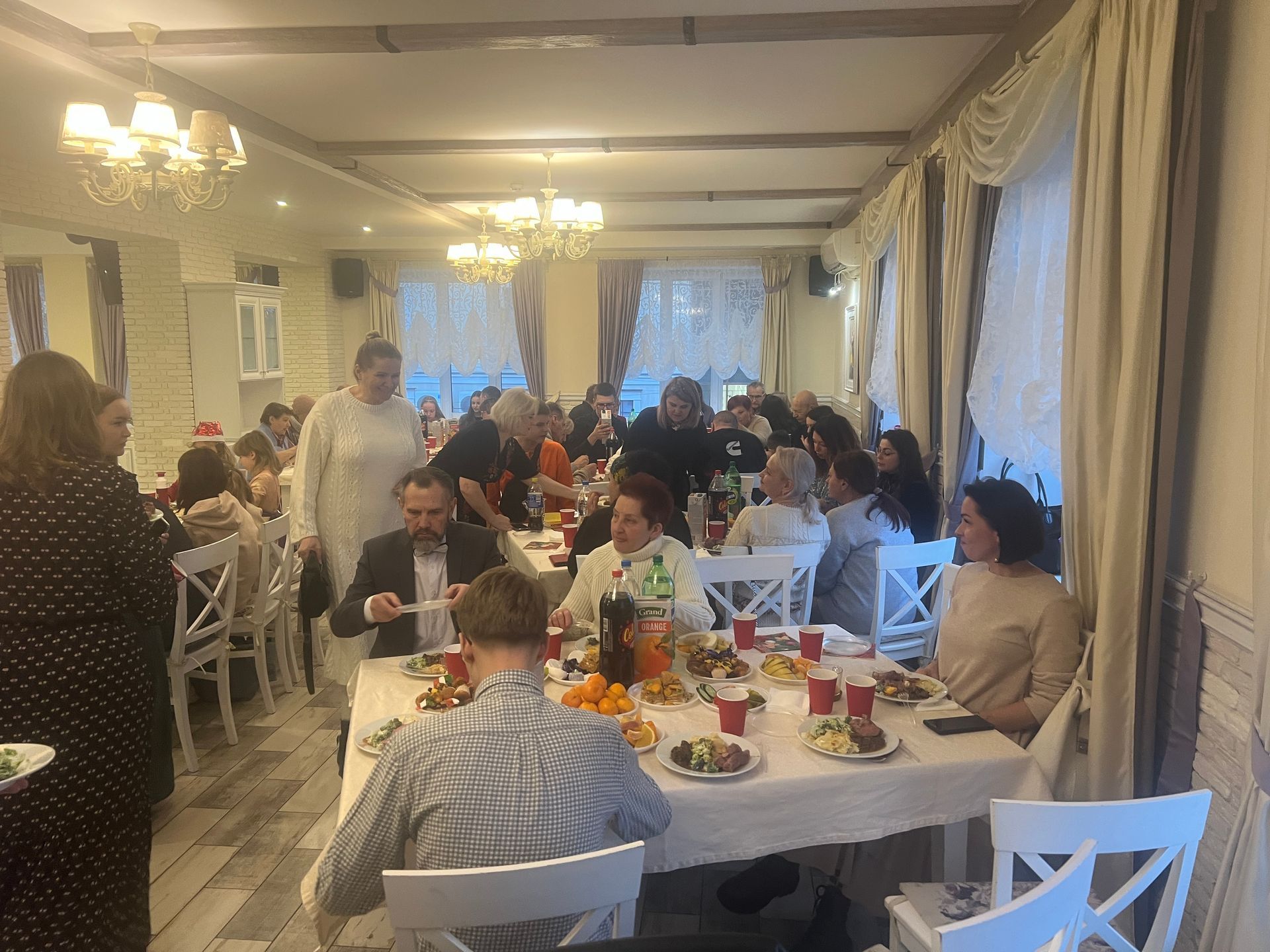 Folk ved et festlig pyntet restaurantbord feirer med mat og drikke.