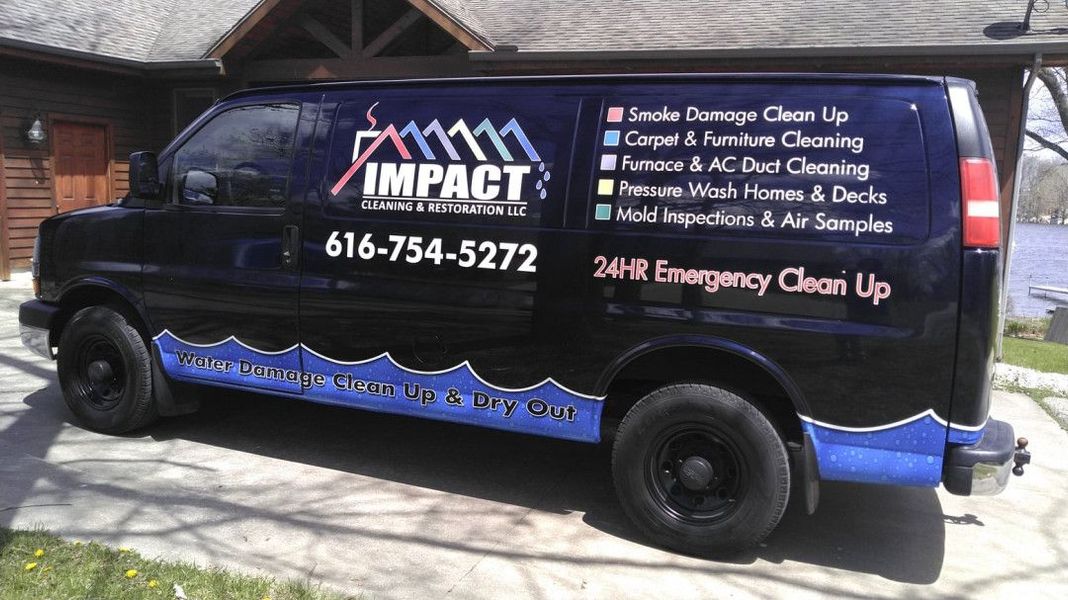 Black IMPACT cleaning service van with company logo and phone number parked on a driveway.