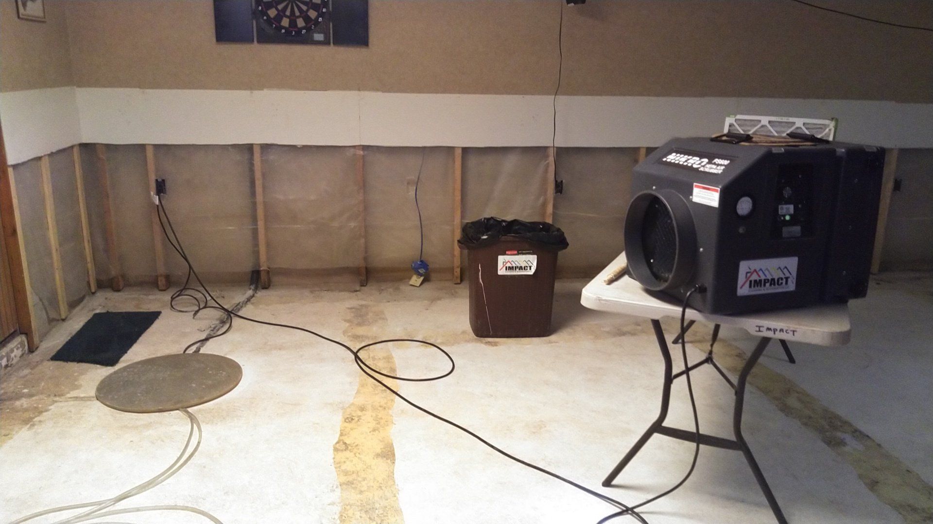 Empty room with a projector and speaker setup, cables on the floor, and a folding table on the right.