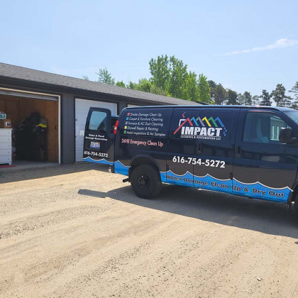 Black IMPACT service van parked outside a garage on a sunny day