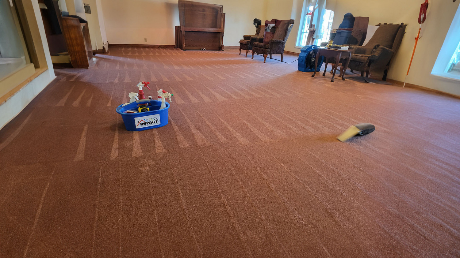 Large carpeted room with toys scattered on the floor and chairs along the walls