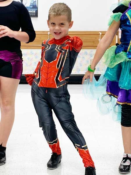 Child in red-and-black superhero costume posing