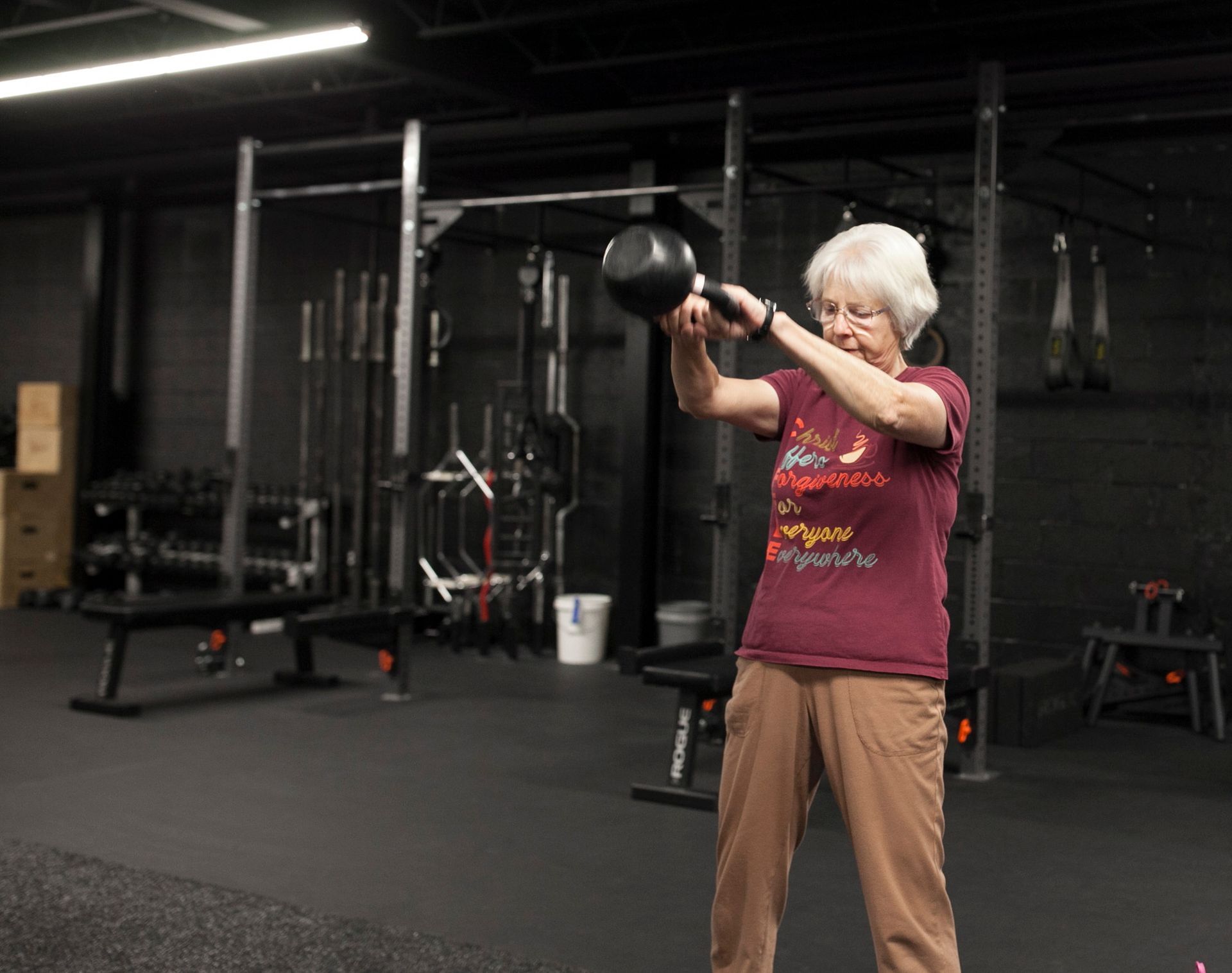 Woman in Vitality Athletics in Ephrata, PA swinging a black kettlebell. She is wearing a maroon shirt and brown pants.