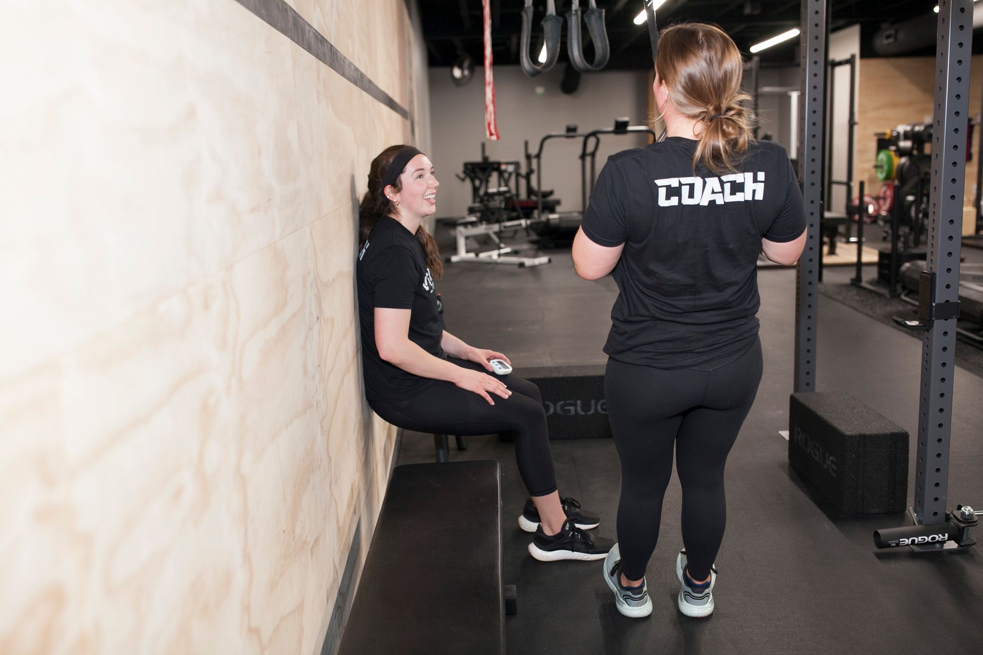 Woman doing wall sit exercise, supervised by a coach in Vitality Athletics in Ephrata, PA