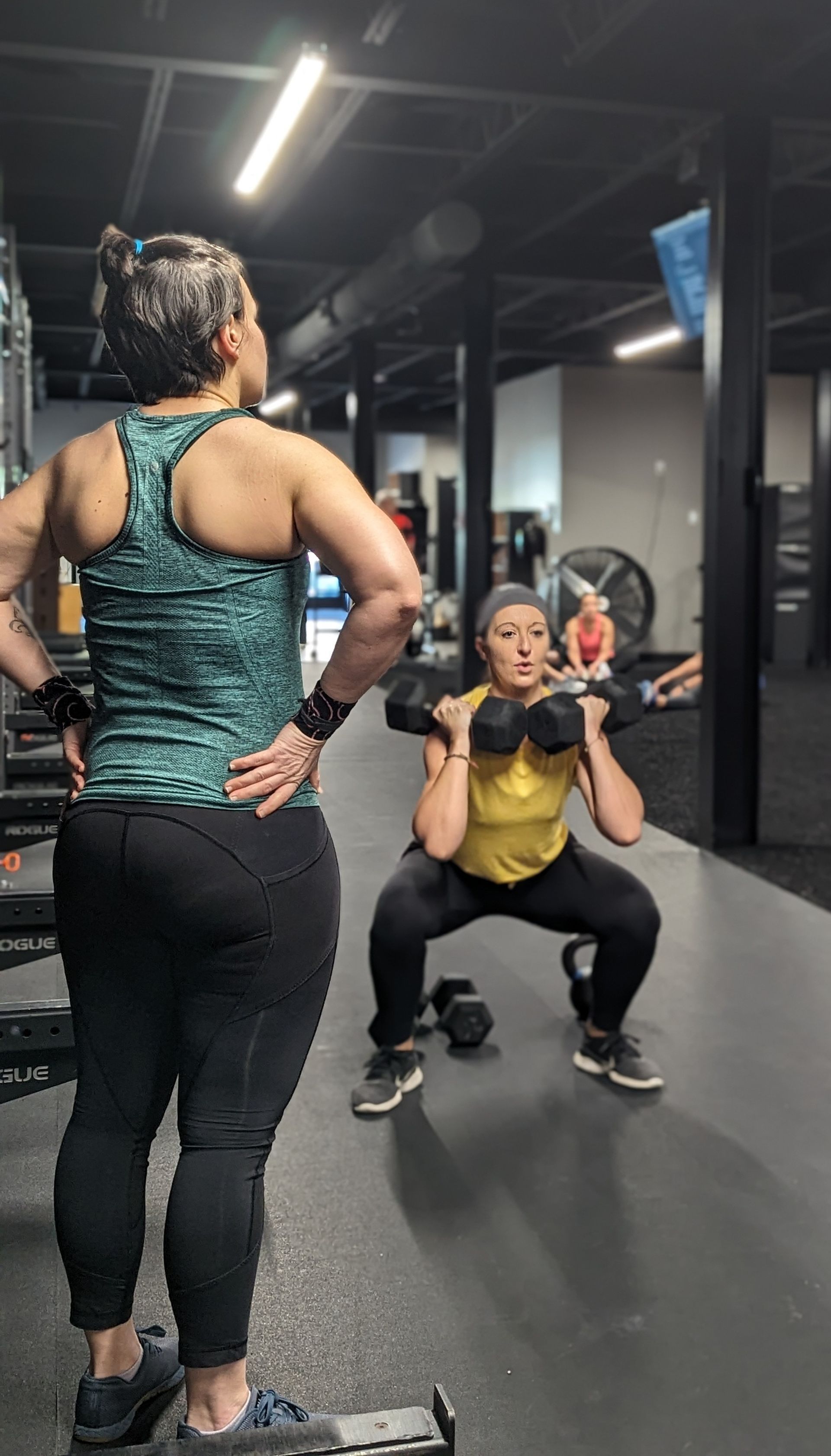 Woman squats with weight, watched by another in Vitality Athletics in Ephrata, PA.