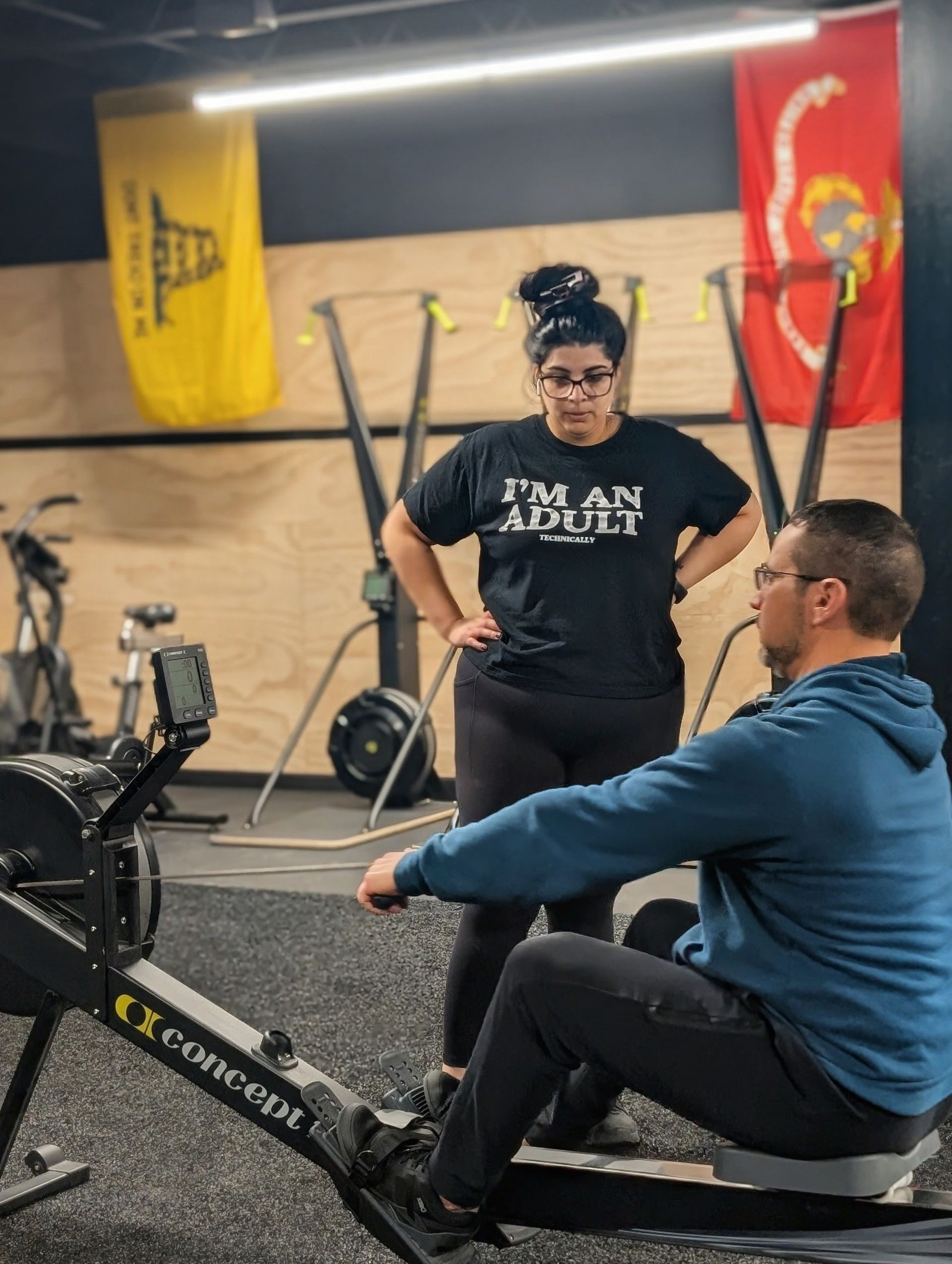 A woman coaches a man on a rowing machine in Vitality Athletics in Ephrata, PA. She wears a