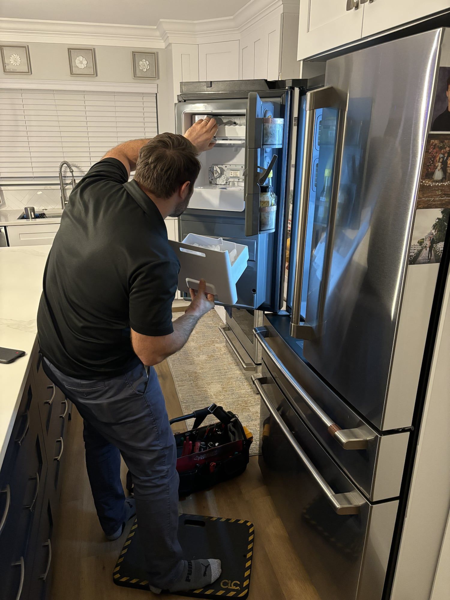 Technician testing a built-in oven with a multimeter in a bright kitchen