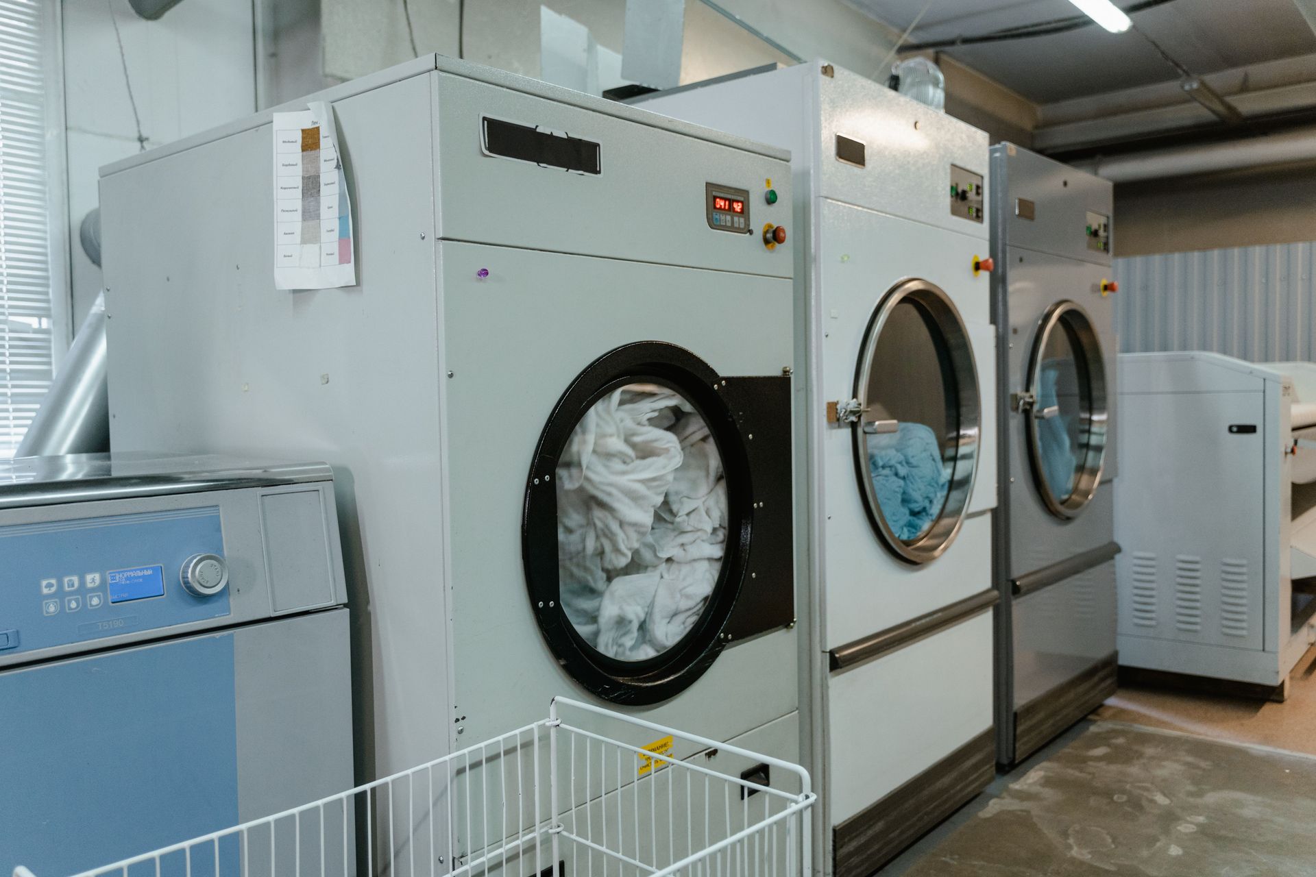 Technician kneels beside a stainless washing machine, inspecting the control panel in a bright modern home