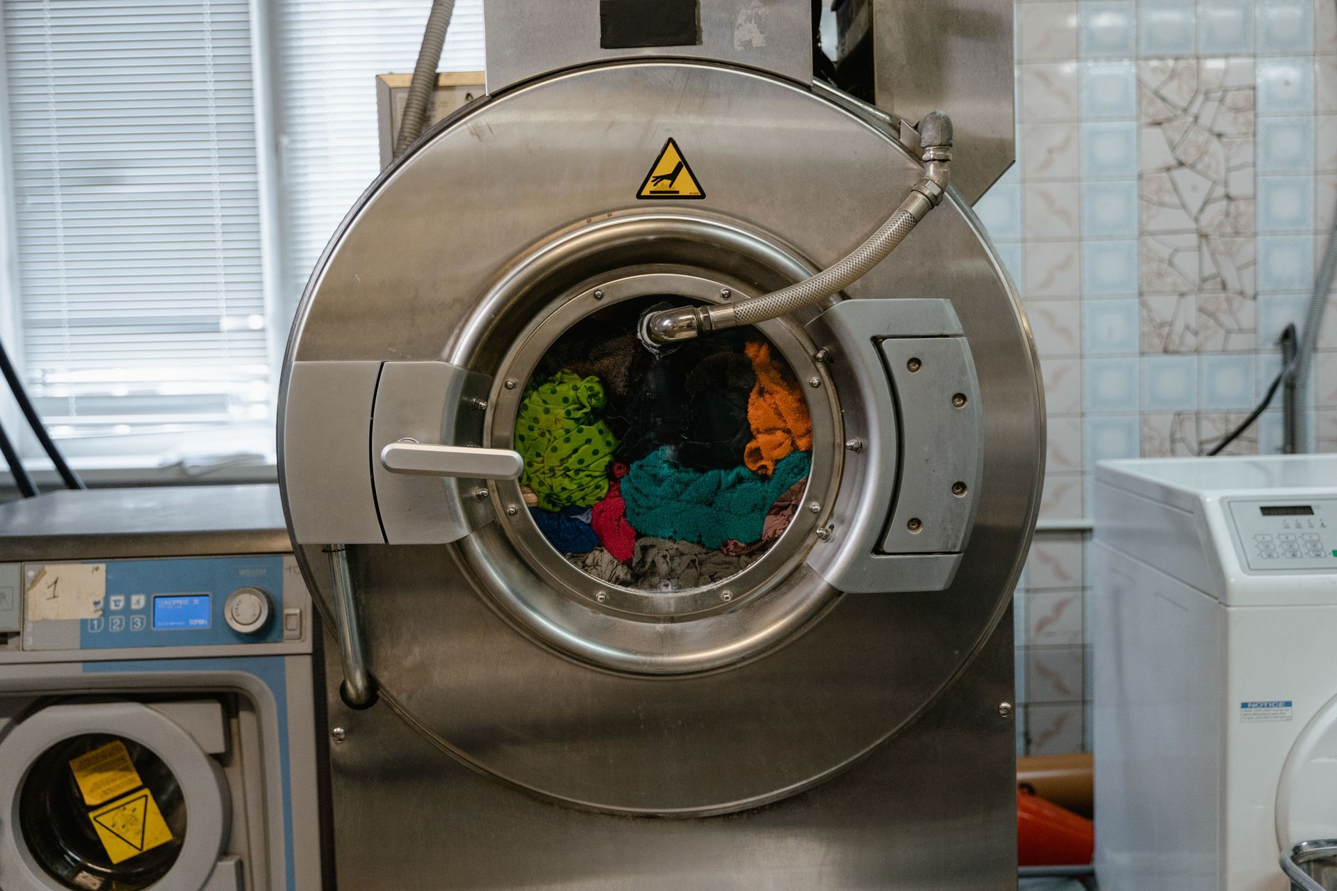 Technician kneels beside a stainless washing machine, inspecting the control panel in a bright modern home