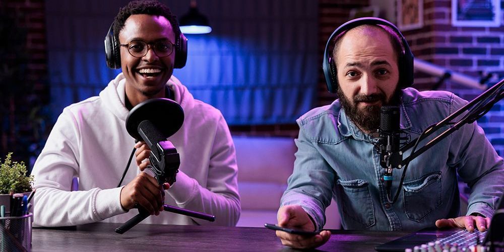 Two man are setting in front of microphone