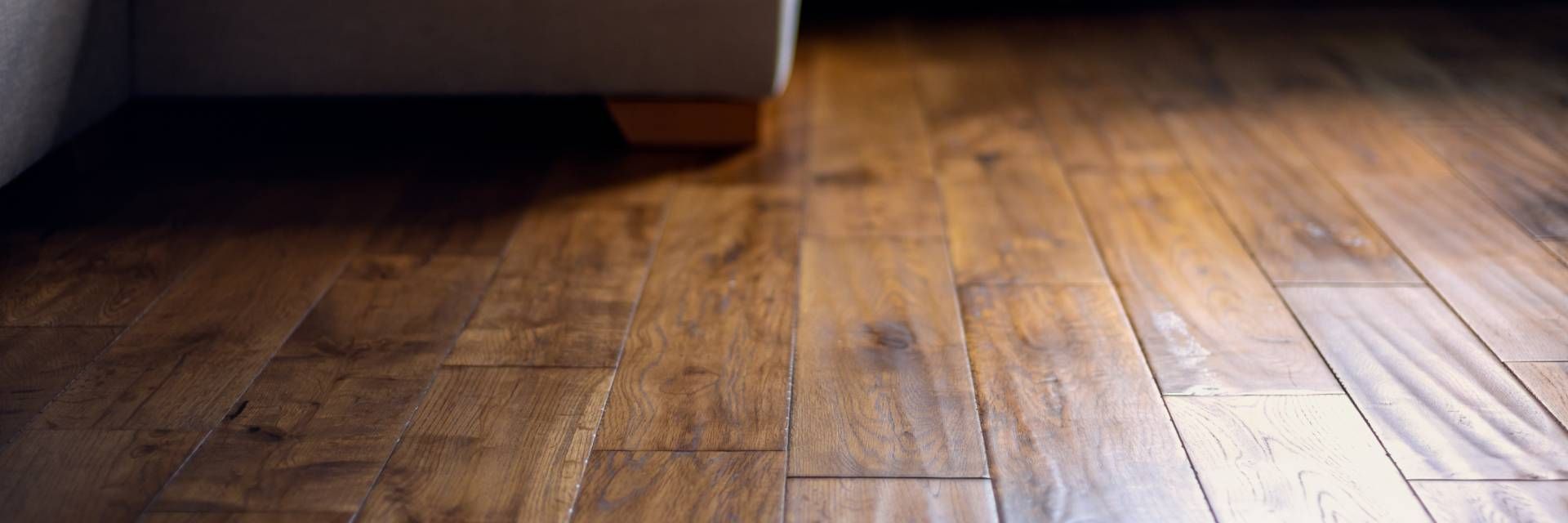 Empty wooden floor with warm light and shadows near a wall