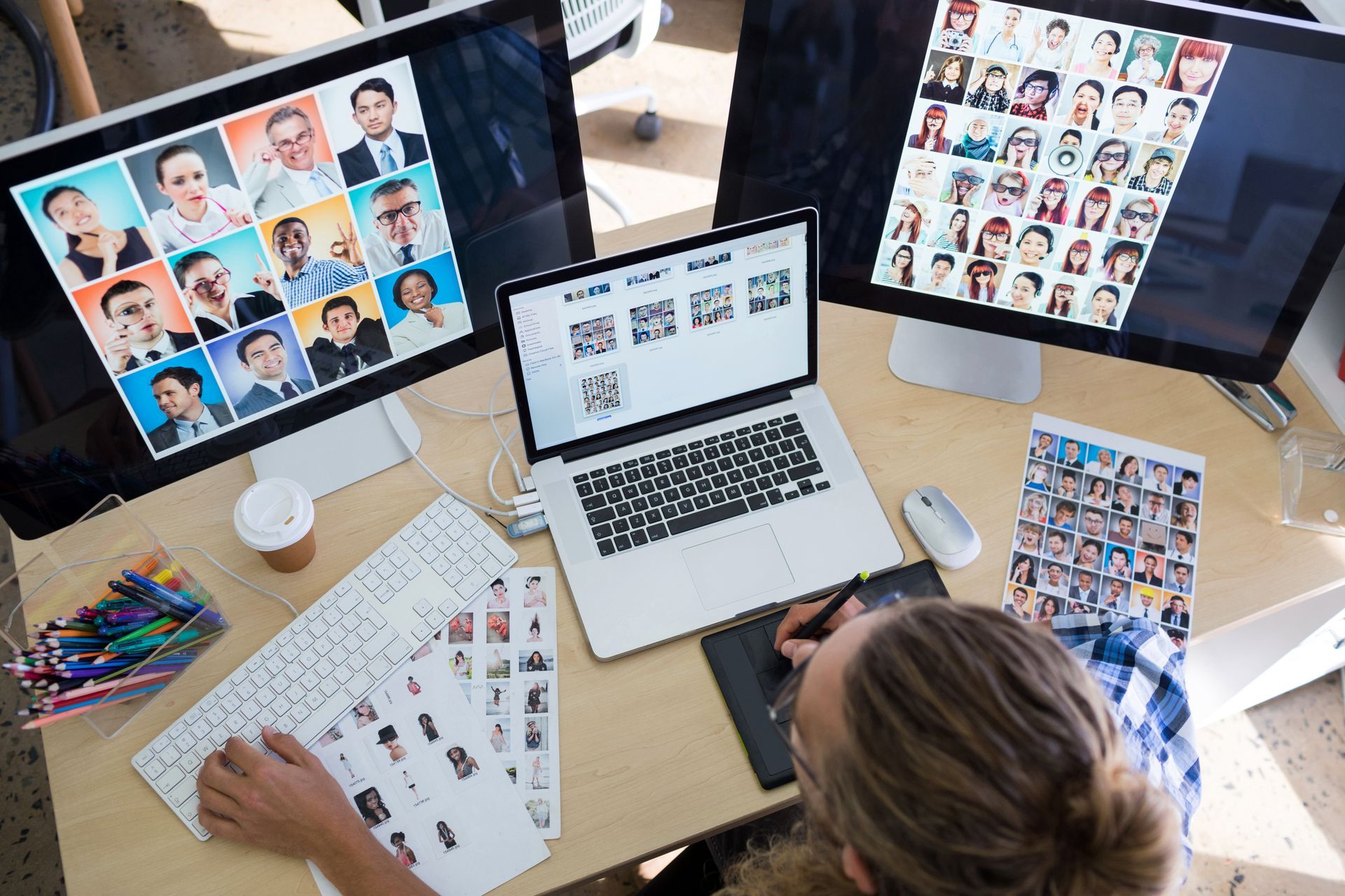 Designer reviewing headshots and layouts on multiple monitors at a work desk