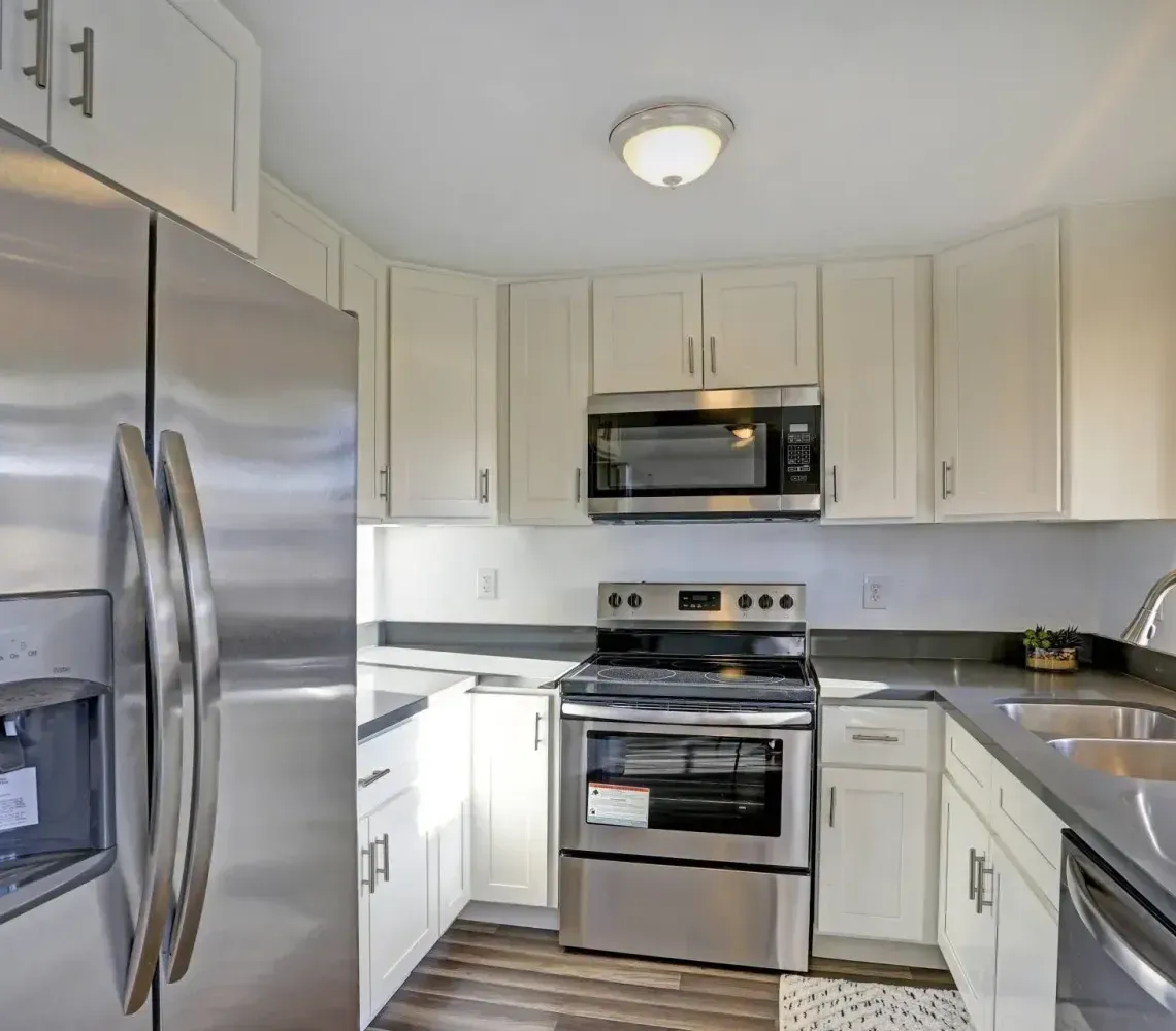 Bright modern kitchen with stainless steel appliances, white cabinets, and a large window over the sink