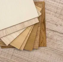 Stack of beige and tan textured paper or fabric swatches on a light wood surface