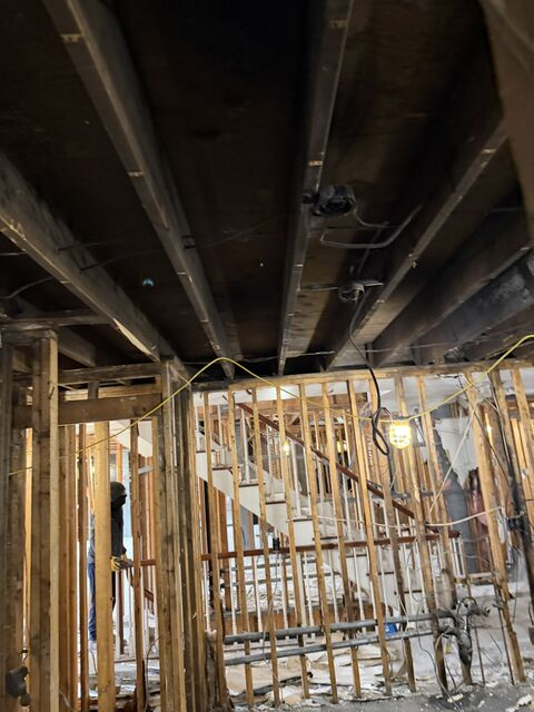 Exposed basement framing with wooden studs and dark overhead beams in a partially unfinished room