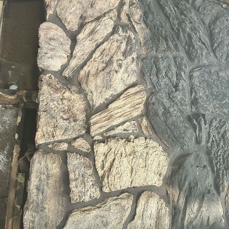 Close-up of a rough gray stone wall with irregular, stacked rocks and visible mortar seams