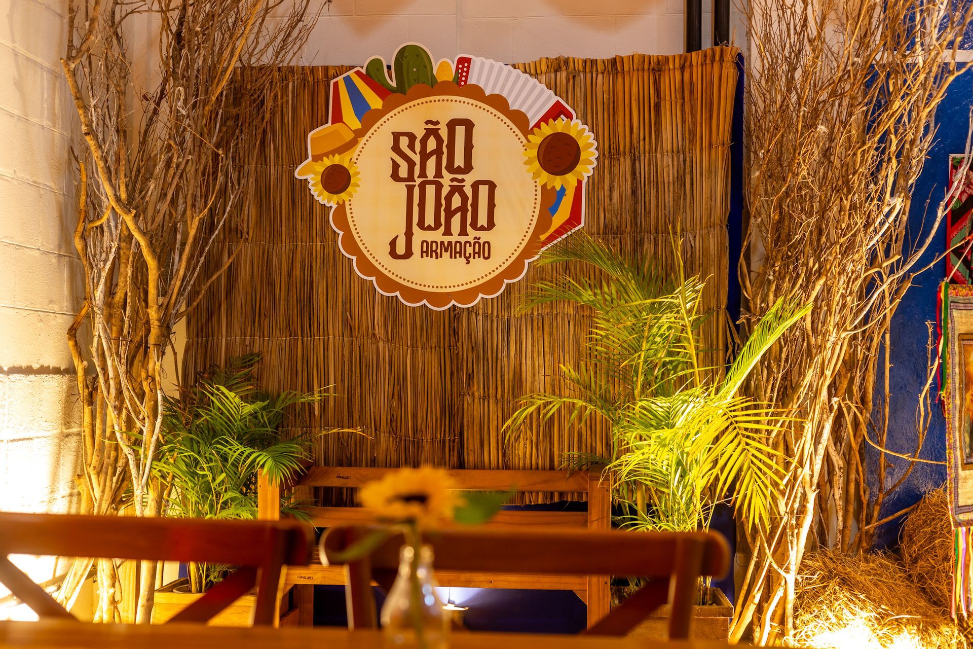 Decoração temática do São João do Armação Resort, com painel rústico de palha, elementos juninos e o letreiro