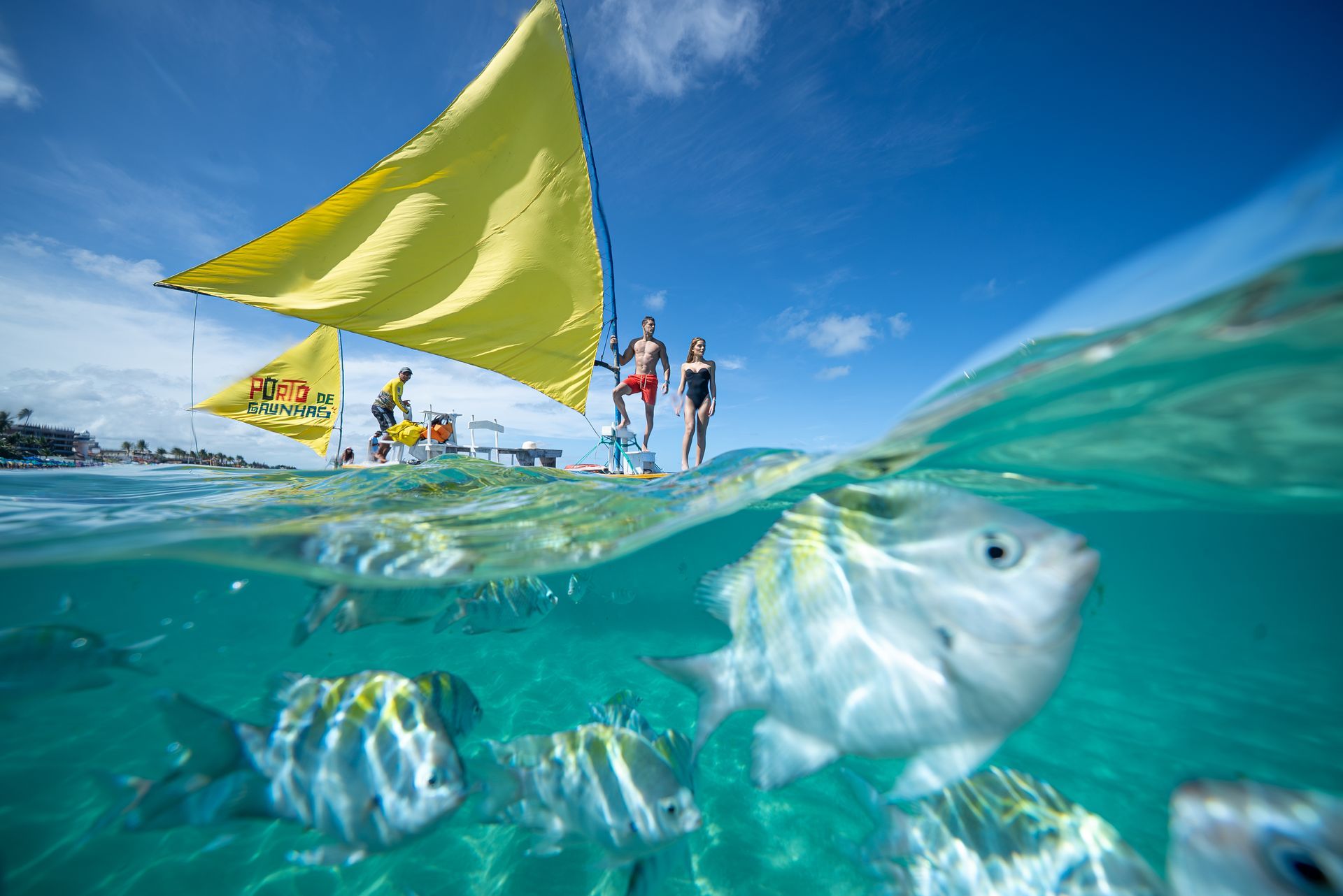 Jangada nas piscinas naturais de Porto de Galinhas, com peixes coloridos em águas cristalinas e visitantes apreciando o passeio.