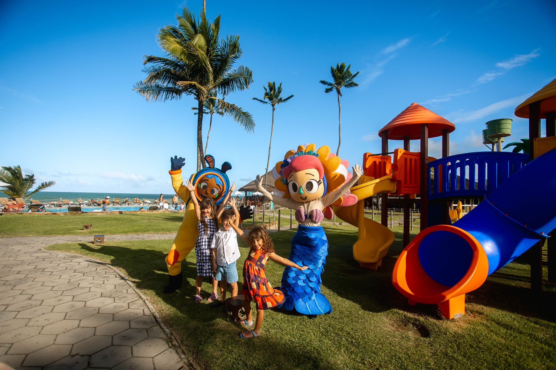 Crianças brincam com mascotes no playground do Armação Resort. Diversão, piscina e praia em Porto de Galinhas.