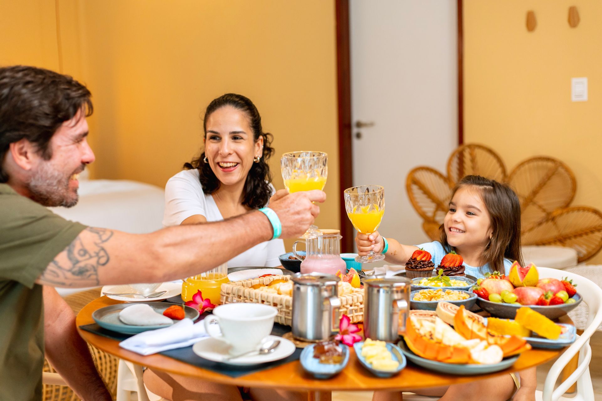 Família brinda no café da manhã do Armação, com mesa farta de frutas, pães e sucos em Porto 