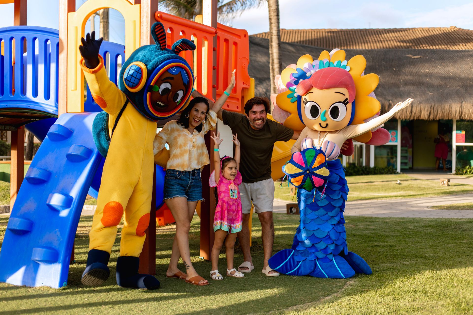 Família posa com mascotes infantis em frente ao playground do Armação Resort.